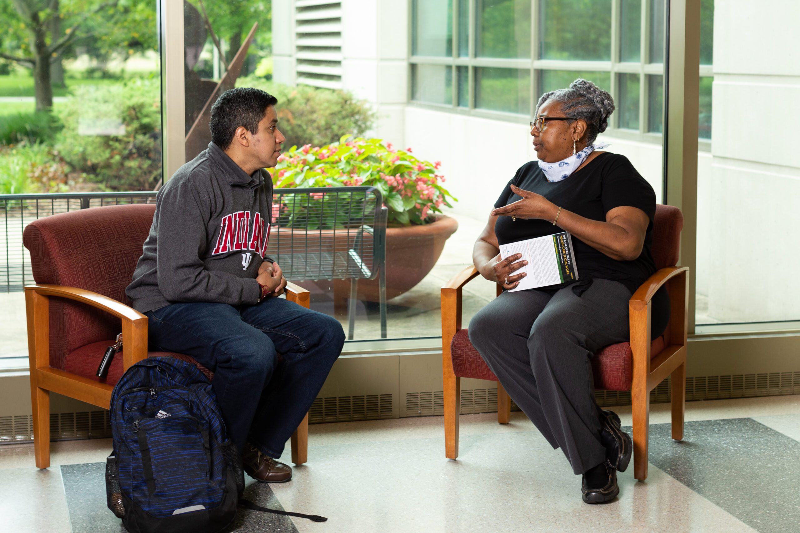 Two people sitting in a school building overlooking a garden